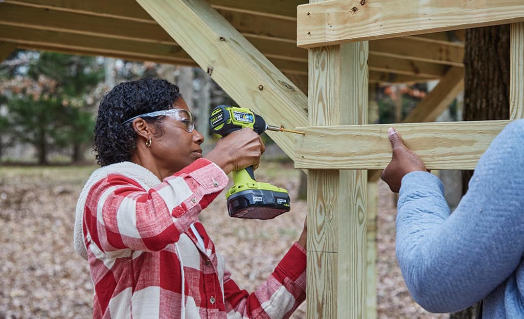 A woman attaches a ladder to the treehouse. A woman attaches a ladder to the treehouse.