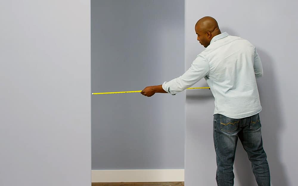 A man uses a tape measure on a doorway. A man uses a tape measure on a doorway.