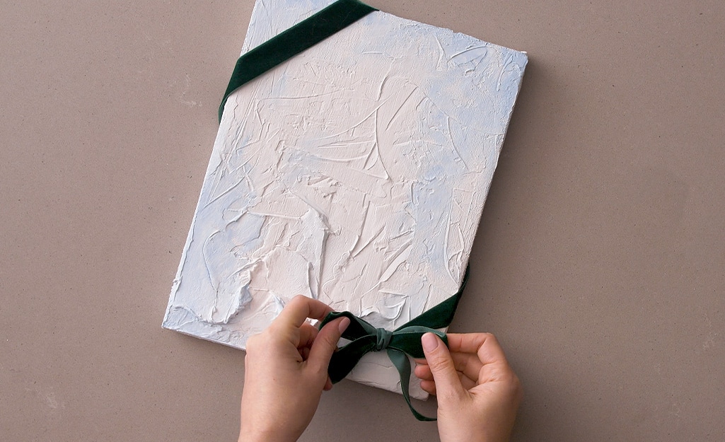 A finished piece of art is wrapped with a green velvet bow. A finished piece of art is wrapped with a green velvet bow.