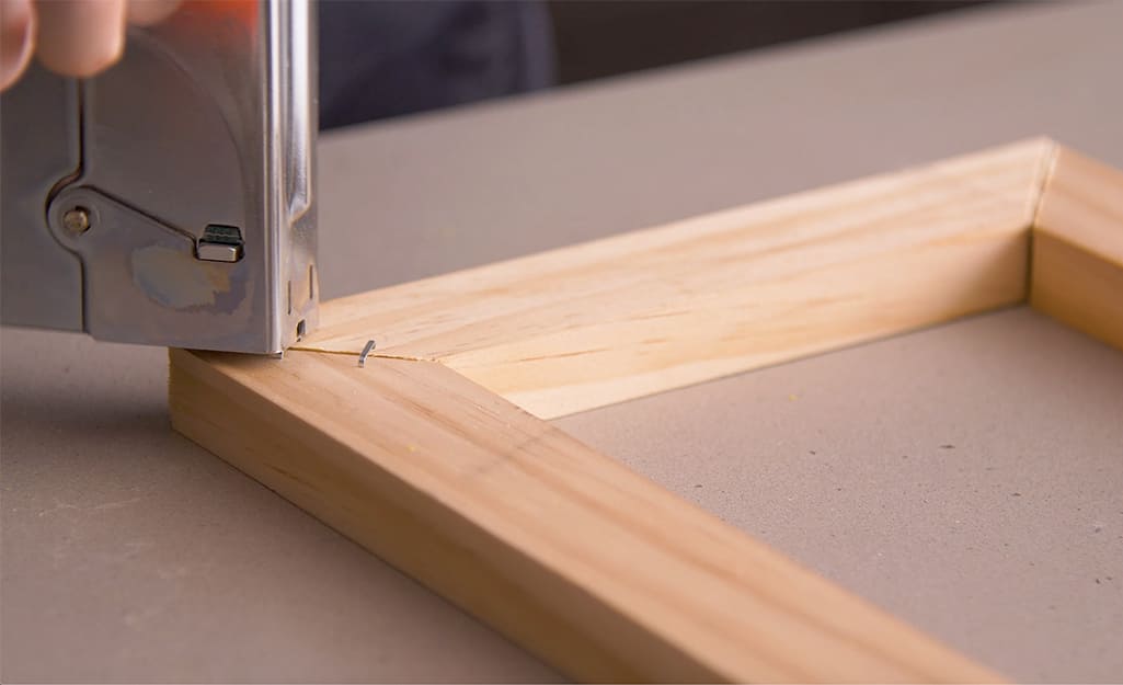 A wood frame is stapled using a staple gun. A wood frame is stapled using a staple gun.