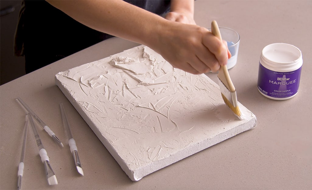 White paint is applied over putty on a canvas. White paint is applied over putty on a canvas.