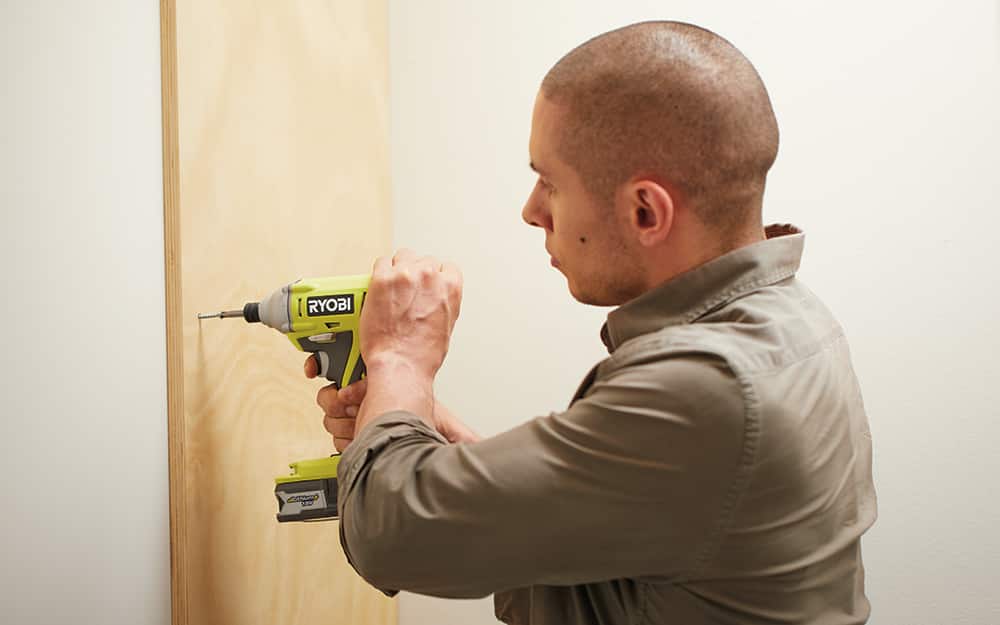 Man using a drill to screw a board to the closet wall. Man using a drill to screw a board to the closet wall.