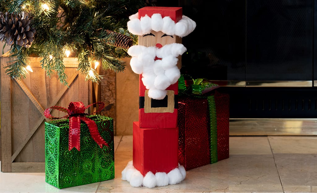 A completed wood block Santa sits near a Christmas tree and presents. A completed wood block Santa sits near a Christmas tree and presents.