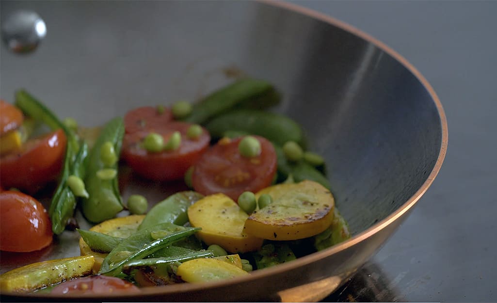 Vegetables are sauteed in a copper frying pan. Vegetables are sauteed in a copper frying pan.