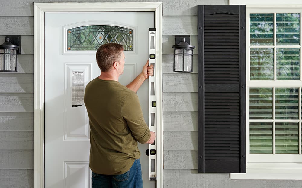 A man test fitting the frame of a home entryway. A man test fitting the frame of a home entryway.
