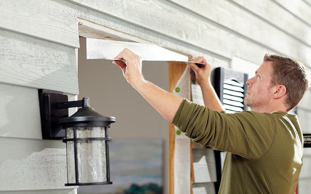 A man adjusting the moulding on the frame of a home entryway. A man adjusting the moulding on the frame of a home entryway.