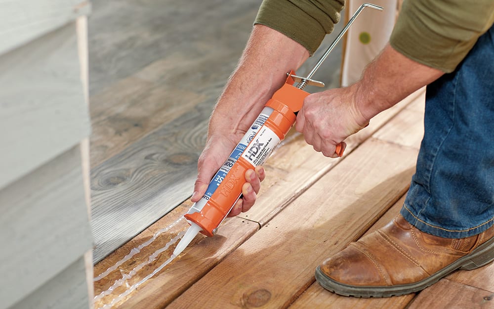 A man caulking the frame of a home entryway. A man caulking the frame of a home entryway.