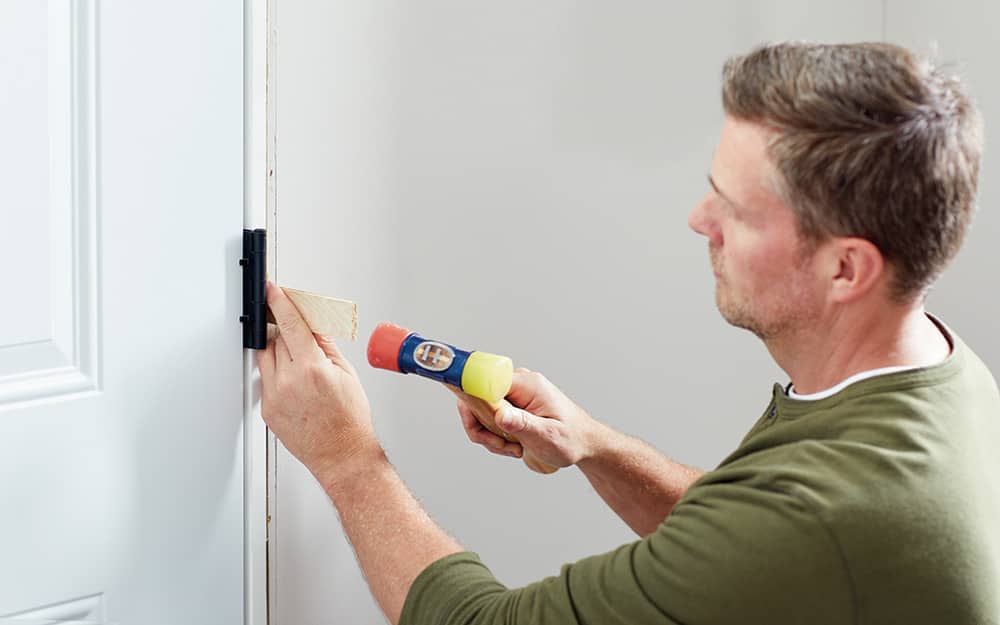 A man shimming a new entry door inside the home. A man shimming a new entry door inside the home.