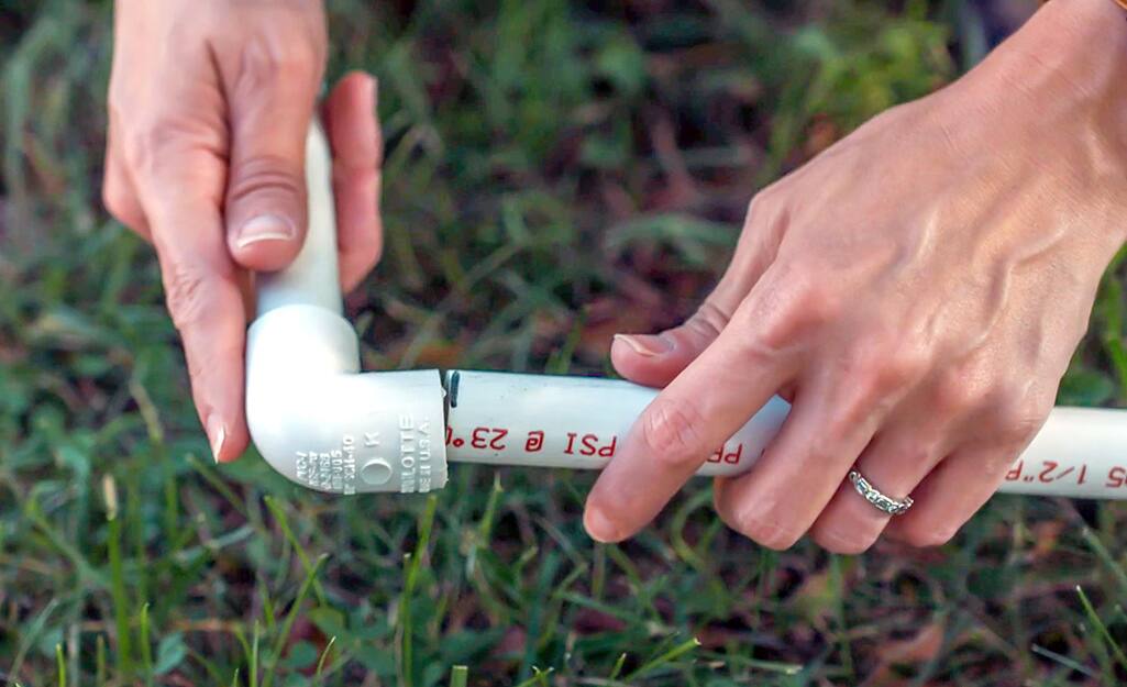 A person connecting PVC pipes with connectors. A person connecting PVC pipes with connectors.