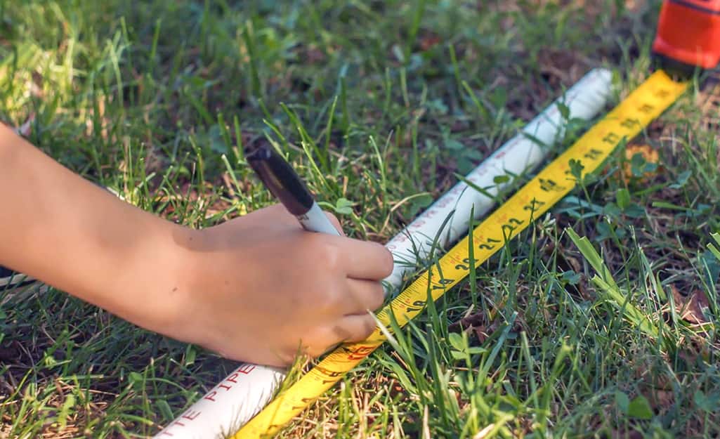 A person marking drill holes in a PVC pipe. A person marking drill holes in a PVC pipe.