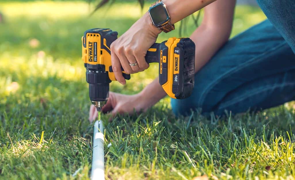 A person drilling holes in a PVC pipe. A person drilling holes in a PVC pipe.