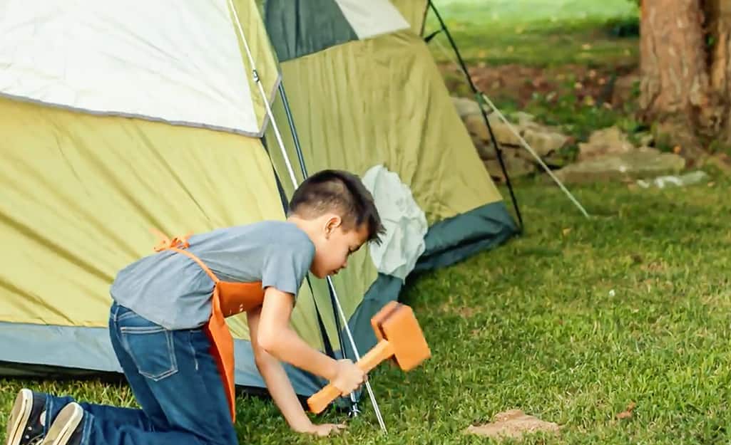 Kid hammers in the sides of the tent. Kid hammers in the sides of the tent.