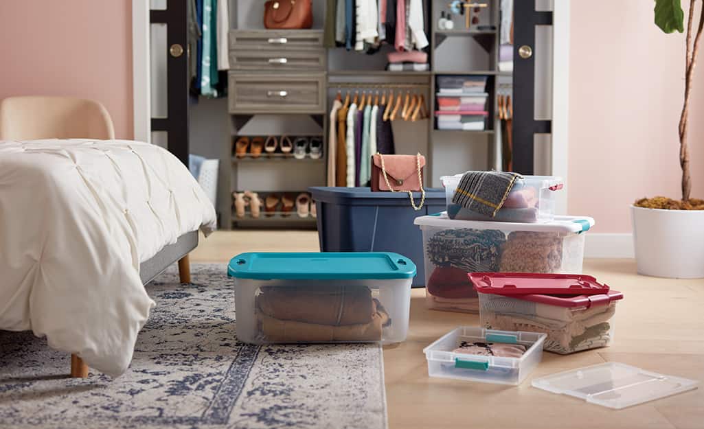Plastic moving bins and storage totes are used to pack a bedroom closet. Plastic moving bins and storage totes are used to pack a bedroom closet.