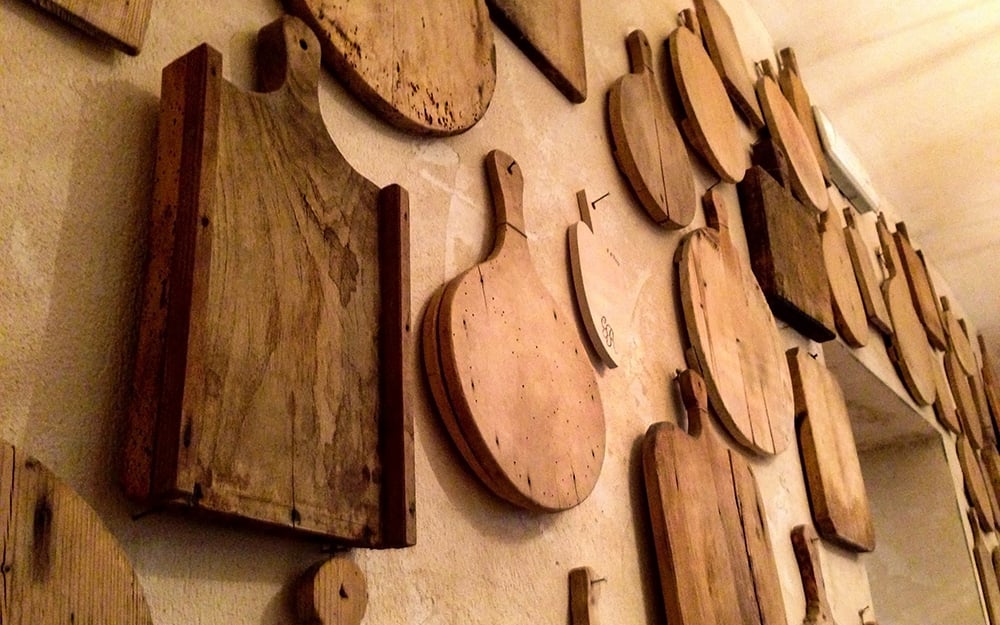 An assortment of cutting boards arranged on a wall. An assortment of cutting boards arranged on a wall.