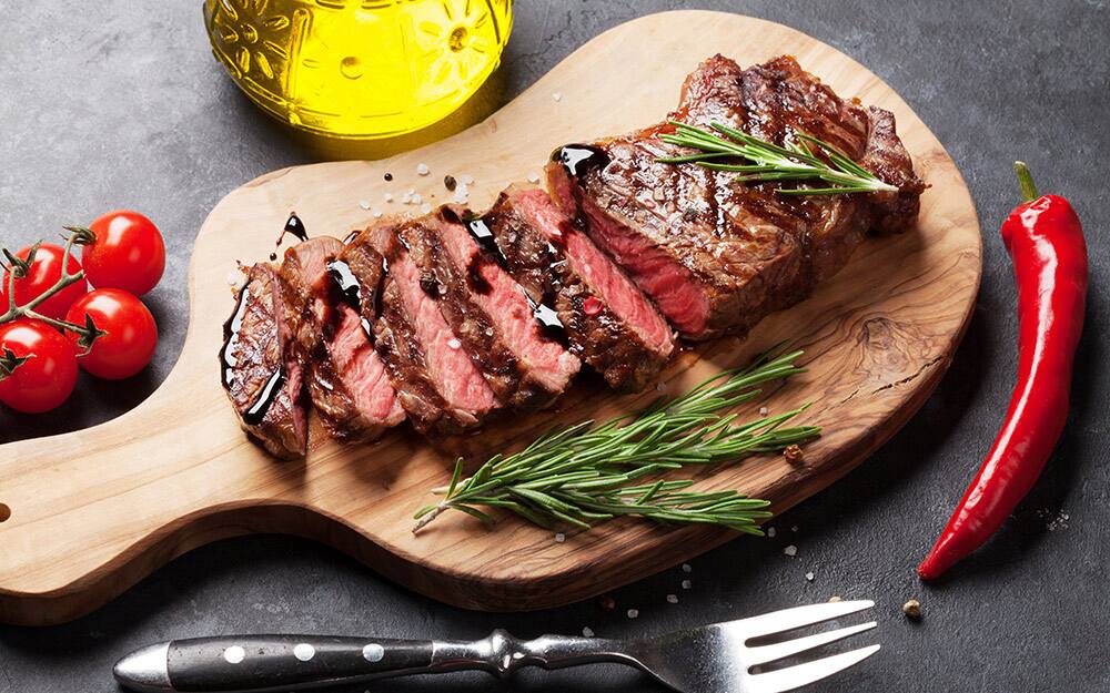 A wood cutting board with a sliced medium steak. A wood cutting board with a sliced medium steak.
