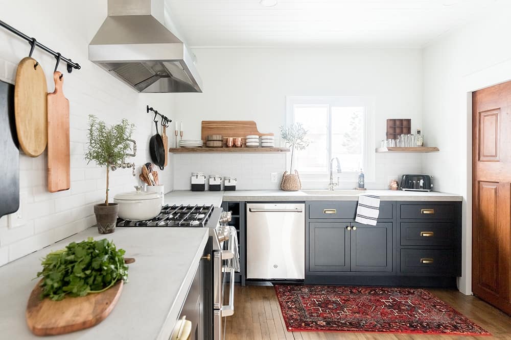 A kitchen with white tile backsplash, dark lower cabinets, and floating wood shelves. A kitchen with white tile backsplash, dark lower cabinets, and floating wood shelves.