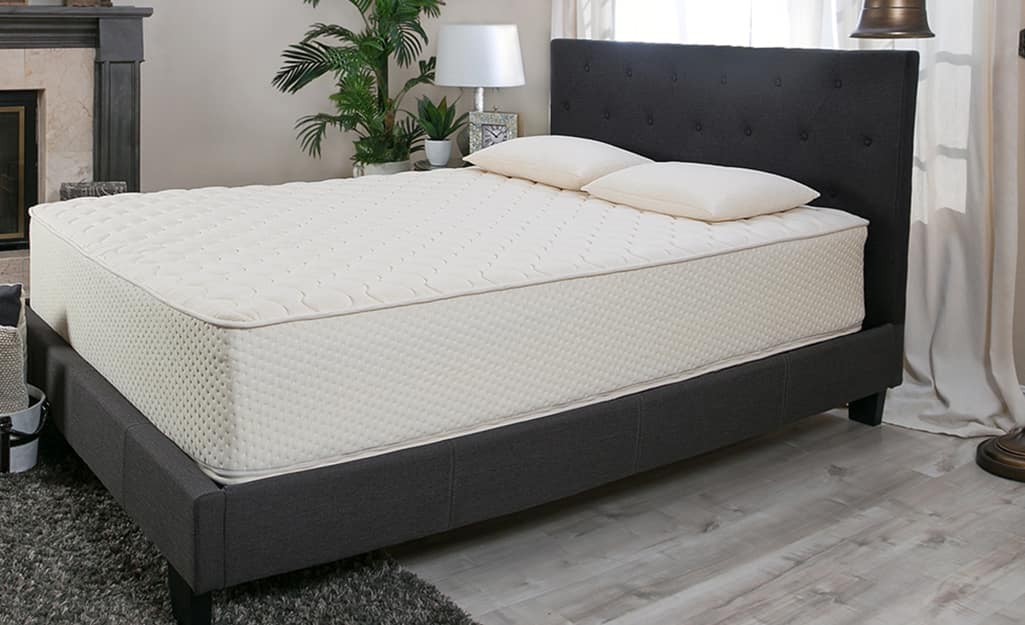 A bedroom with a latex mattress on a fabric bedframe. A bedroom with a latex mattress on a fabric bedframe.