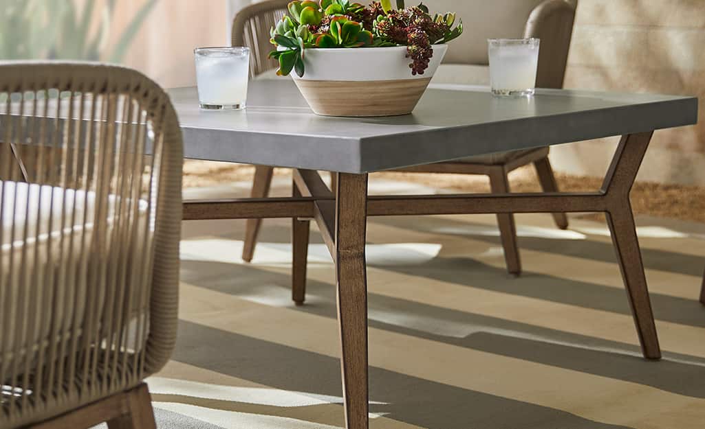 A coffee table with a gray top and wooden legs on a patio. A coffee table with a gray top and wooden legs on a patio.
