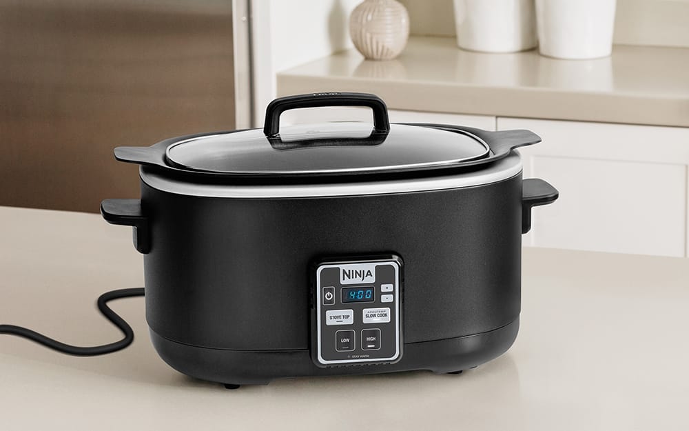 A black slow cooker on a counter. A black slow cooker on a counter.