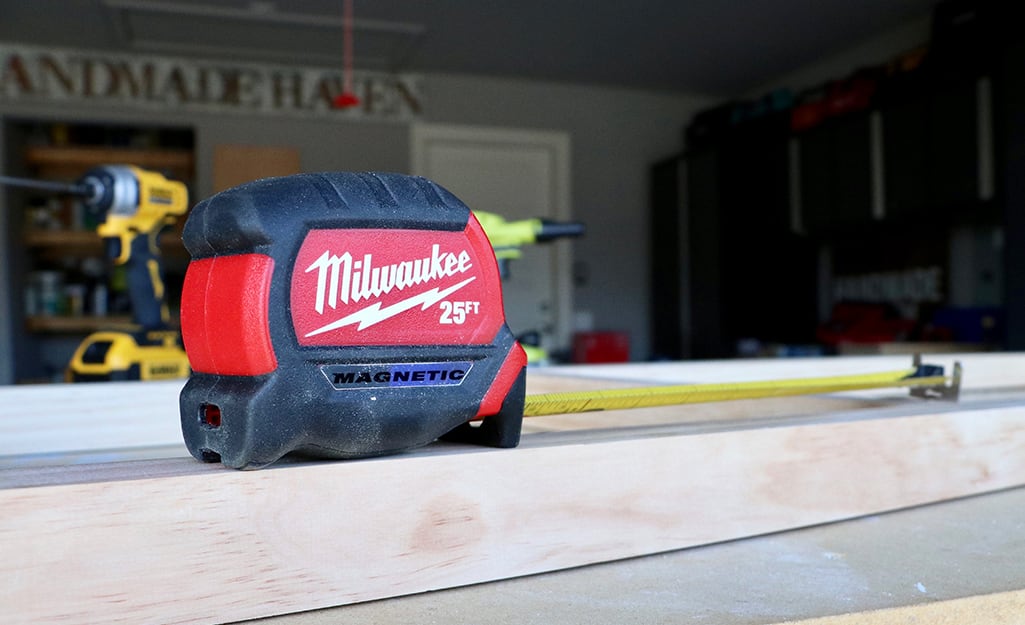 A tape measure sits on a piece of lumber in a garage. A tape measure sits on a piece of lumber in a garage.