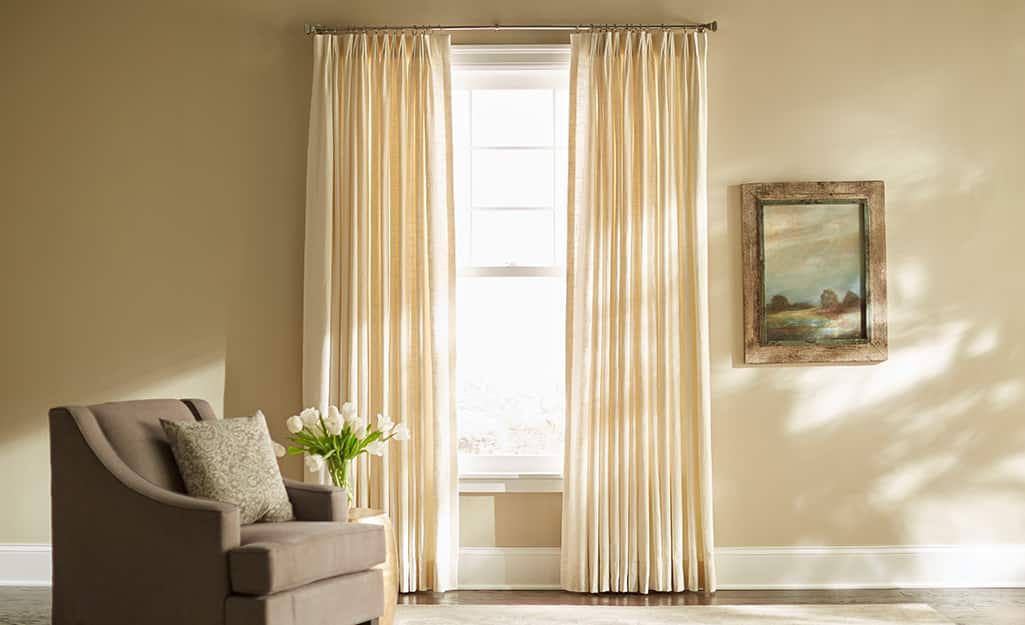 Cream-colored pleated curtains over a living room window. Cream-colored pleated curtains over a living room window.