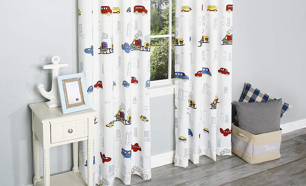 White curtains with multi-colored cars on them in a child's room. White curtains with multi-colored cars on them in a child's room.