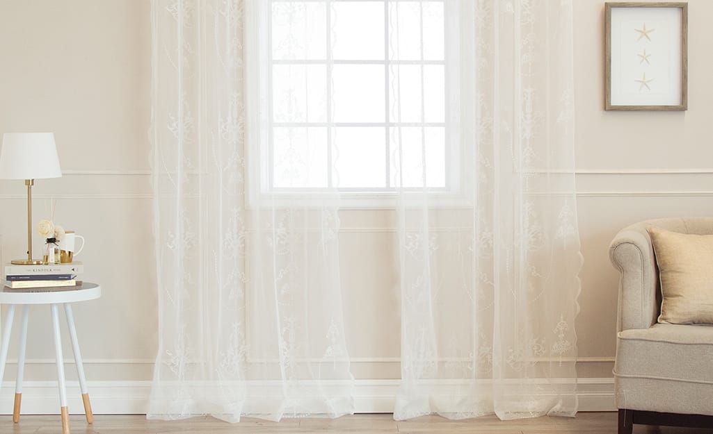 Sheer, white curtains over a living room window. Sheer, white curtains over a living room window.