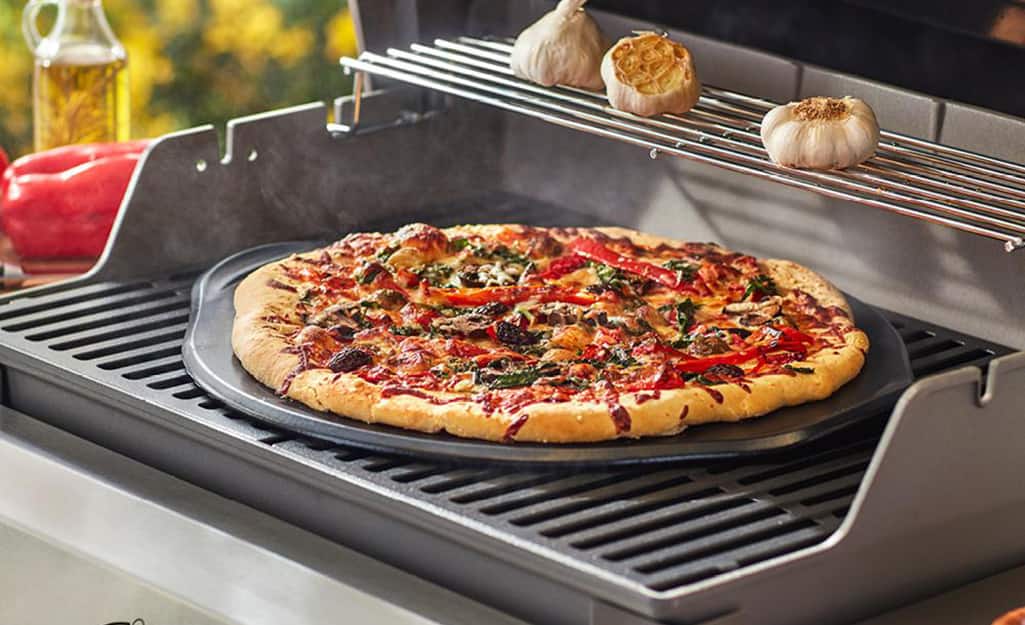 A pizza is grilled on an oven by using a pizza stone. A pizza is grilled on an oven by using a pizza stone.