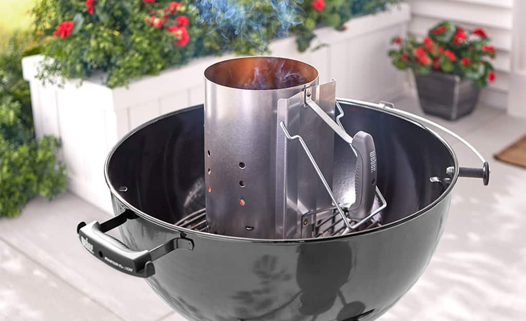 A chimney starter is used on a charcoal grill. A chimney starter is used on a charcoal grill.