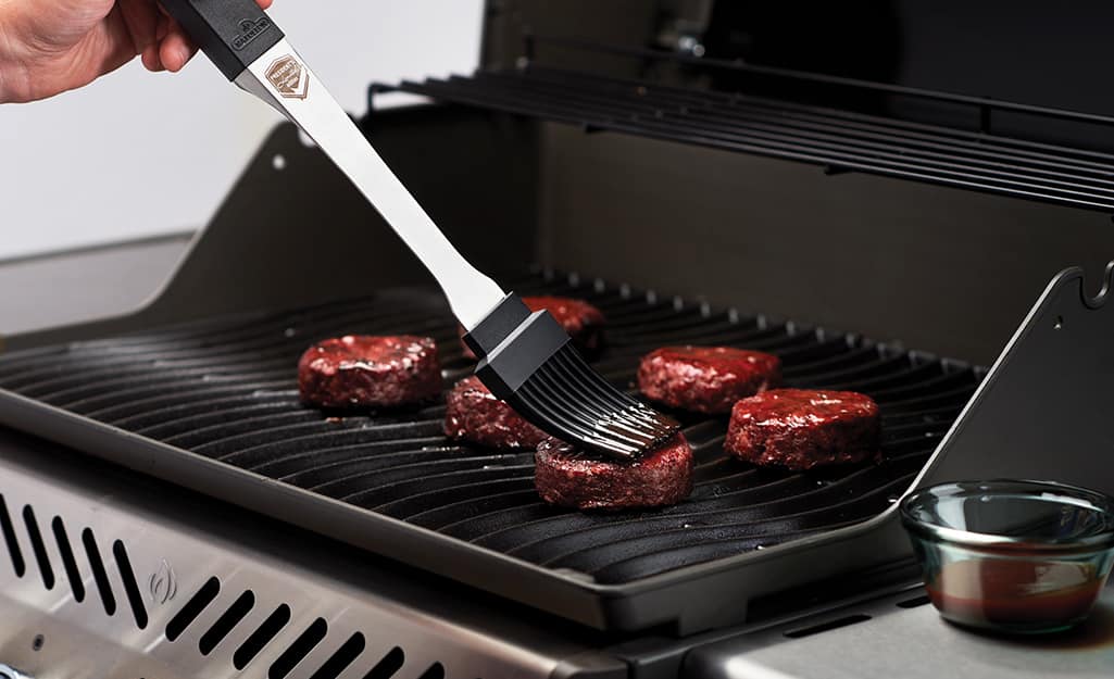 A person uses a silicone-bristled basting brush on meat. A person uses a silicone-bristled basting brush on meat.