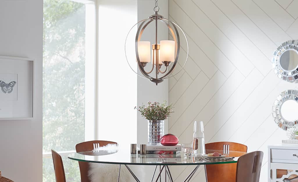 A Hampton Bay chandelier lighting fixture over a glass-topped table with chairs. A Hampton Bay chandelier lighting fixture over a glass-topped table with chairs.
