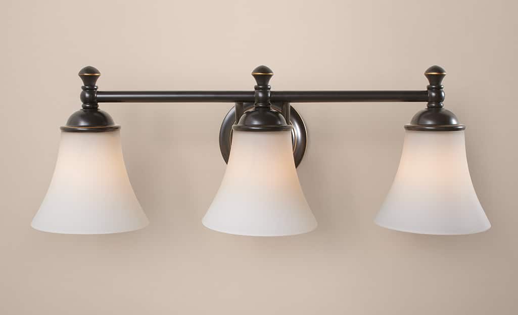 A Hampton Bay wall sconce with three down lights with frosted shades. A Hampton Bay wall sconce with three down lights with frosted shades.