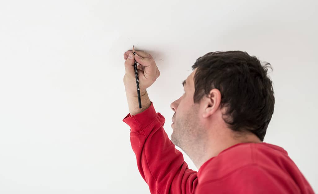 A person marks the spot to install a mounting bracket. A person marks the spot to install a mounting bracket.