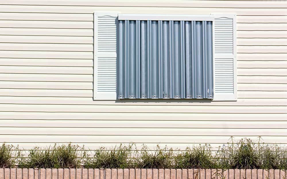 A metal barricade covers a window for storm protection. A metal barricade covers a window for storm protection.