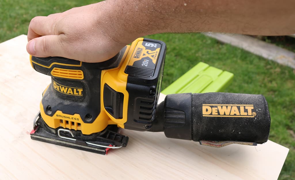 Someone using a cordless sheet sander to sand a board. Someone using a cordless sheet sander to sand a board.