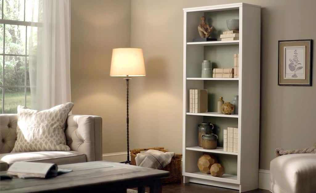 A five-shelf bookshelf stands in a furnished living room. A five-shelf bookshelf stands in a furnished living room.