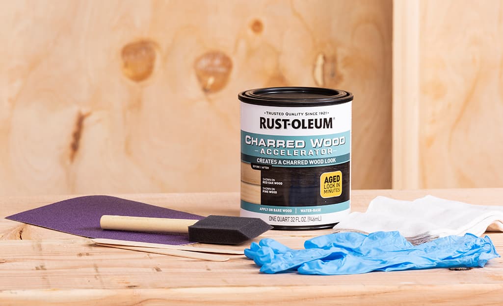 A can of wood stain and wood staining supplies sit on a piece of wood. A can of wood stain and wood staining supplies sit on a piece of wood.