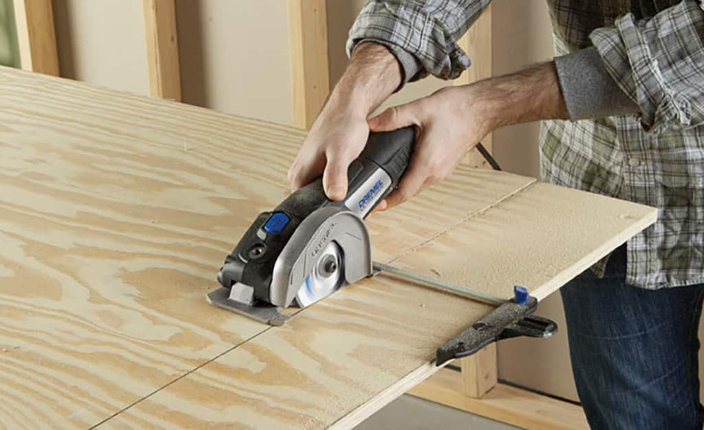 A man uses a handheld circular saw to cut a board. A man uses a handheld circular saw to cut a board.
