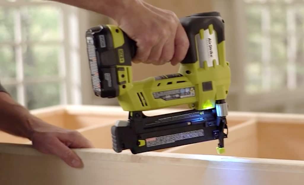 Someone using a nail gun to fasten the face frame of a bookshelf. Someone using a nail gun to fasten the face frame of a bookshelf.