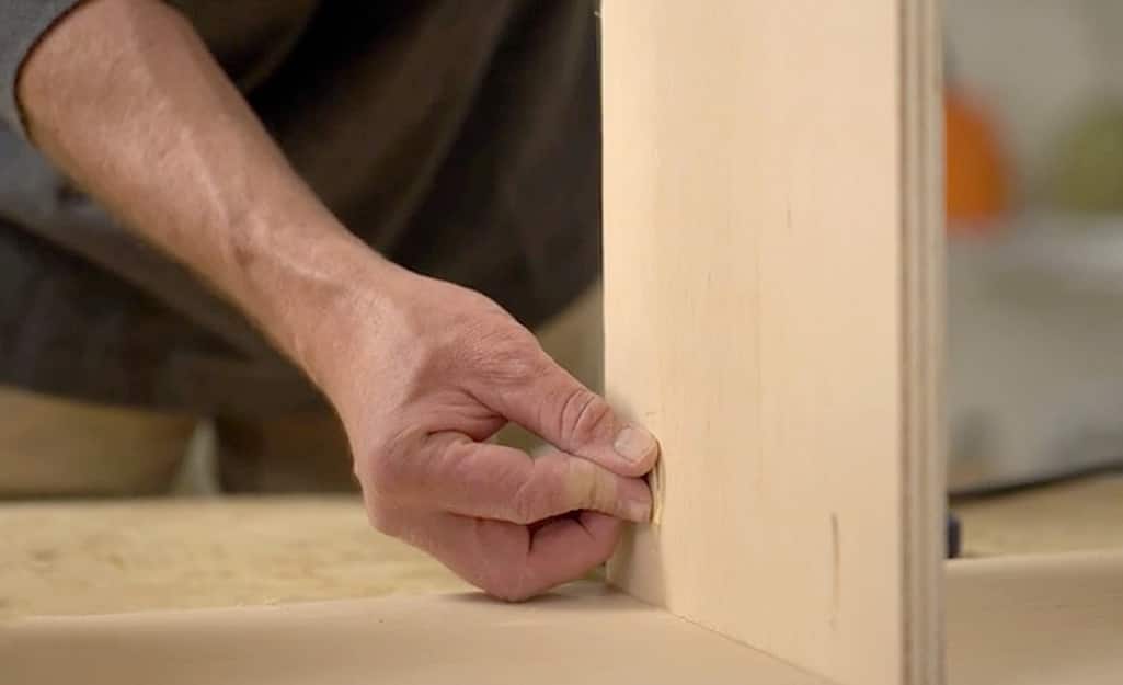Someone inserting pocket hole plugs into a board to hide screws. Someone inserting pocket hole plugs into a board to hide screws.