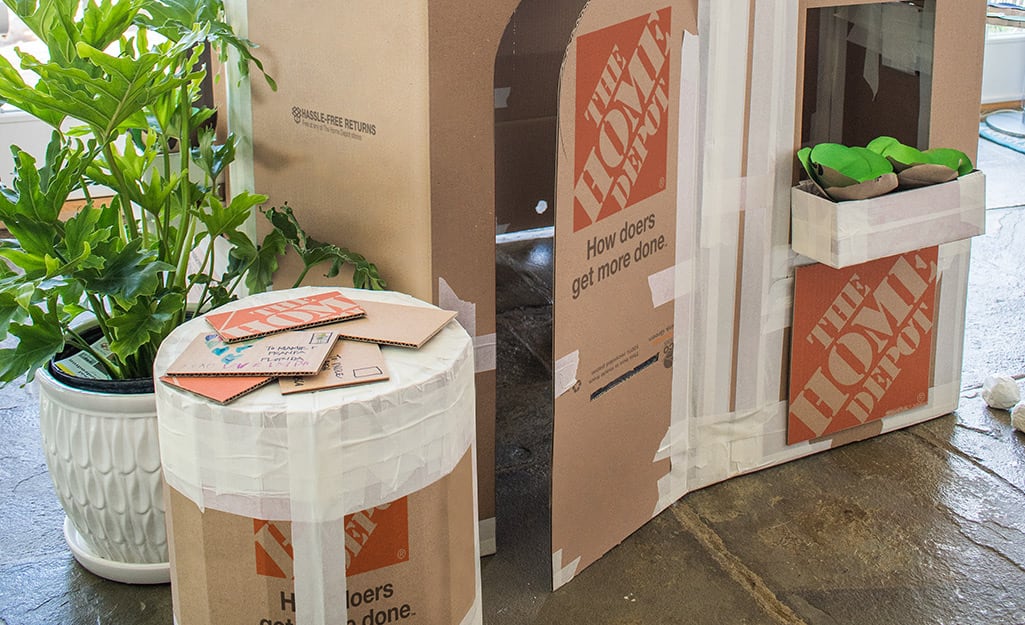 A cardboard play ottoman next to a cardboard playhouse. A cardboard play ottoman next to a cardboard playhouse.