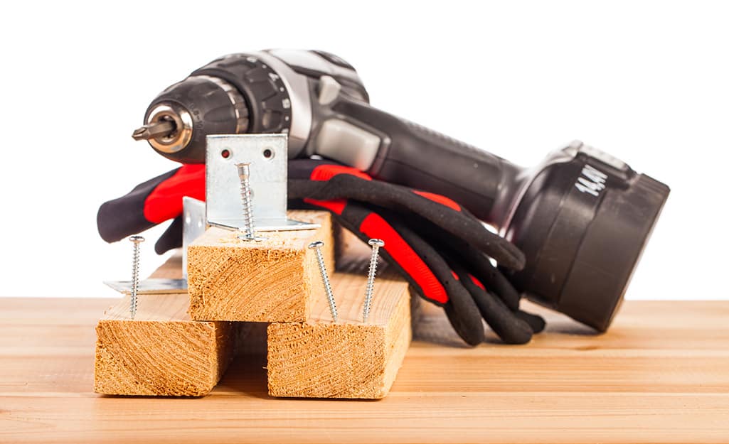 A cordless drill resting on top of wood boards. A cordless drill resting on top of wood boards.