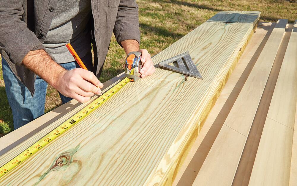 A person measuring wood with a tape measure. A person measuring wood with a tape measure.