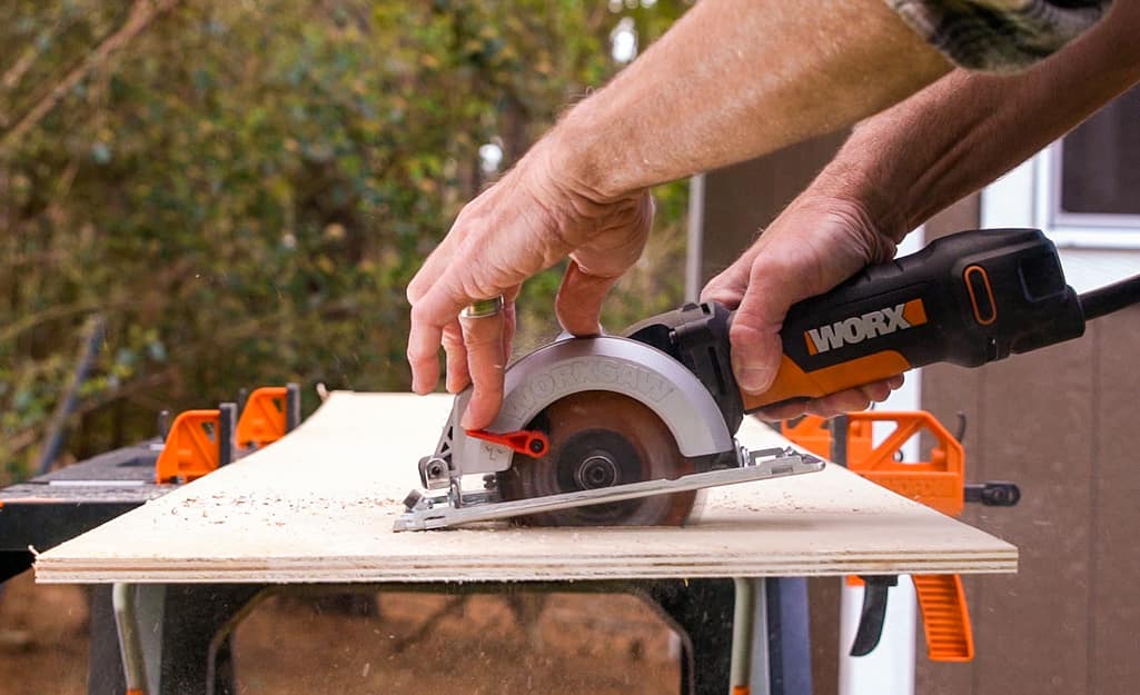 A person cutting a sheet of plywood. A person cutting a sheet of plywood.