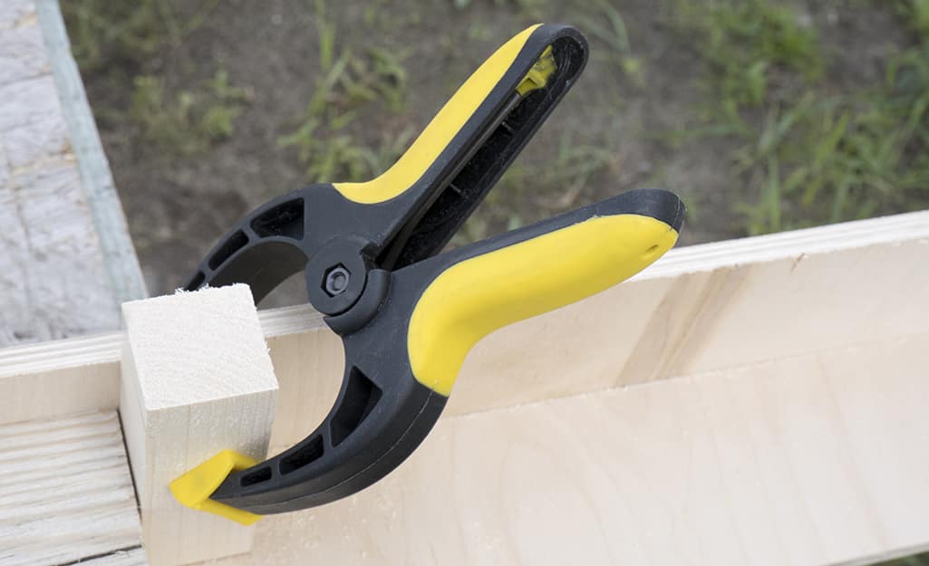A clamp holding two pieces of wood together. A clamp holding two pieces of wood together.
