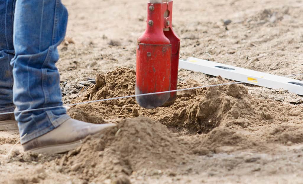 A hole being dug in the ground using a post hole digger. A hole being dug in the ground using a post hole digger.