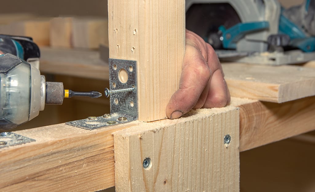 Man attaches a deck board to an inner joist with a power drill. Man attaches a deck board to an inner joist with a power drill.
