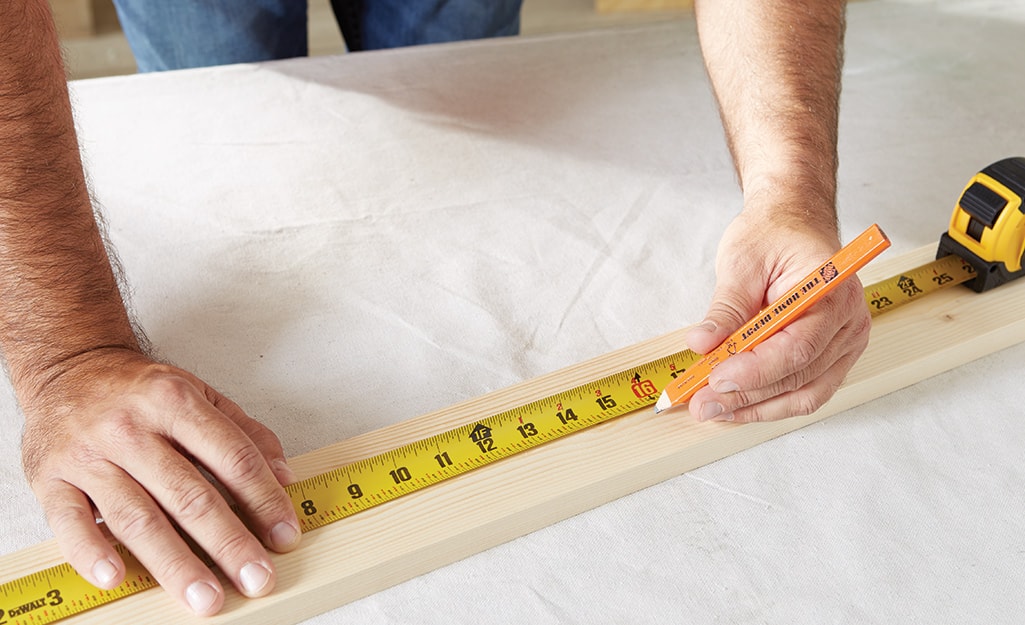 A man uses a pencil and measuring tape to measure and mark wood. A man uses a pencil and measuring tape to measure and mark wood.