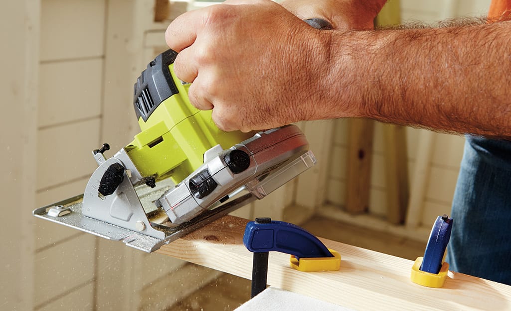 A person uses a circular saw to cut wood. A person uses a circular saw to cut wood.
