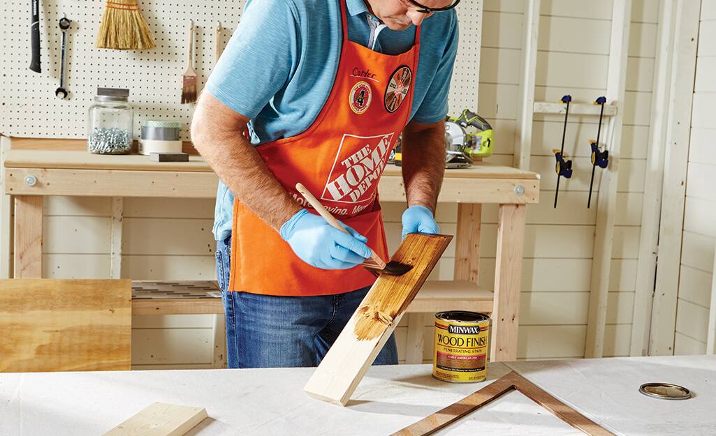 A man stains the boards. A man stains the boards.